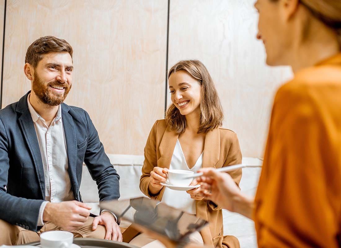 Insurance Agency Insurance - Couple in a Meeting With Insurance Agent Signing Contract Documents in a Modern Office With Lots of Sunlight