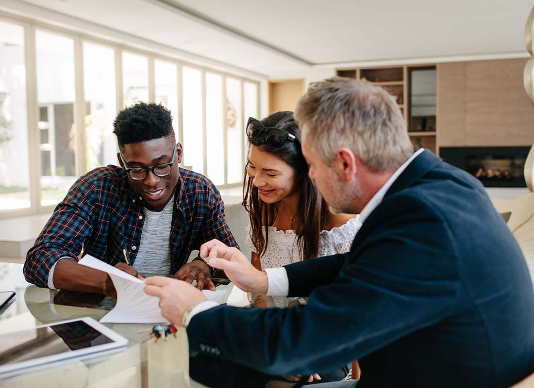 Investment Advisor Insurance - Young Couple Talking With a Financial Advisor Offering Advice and Financial Counseling While Using a Digital Tablet in the Office