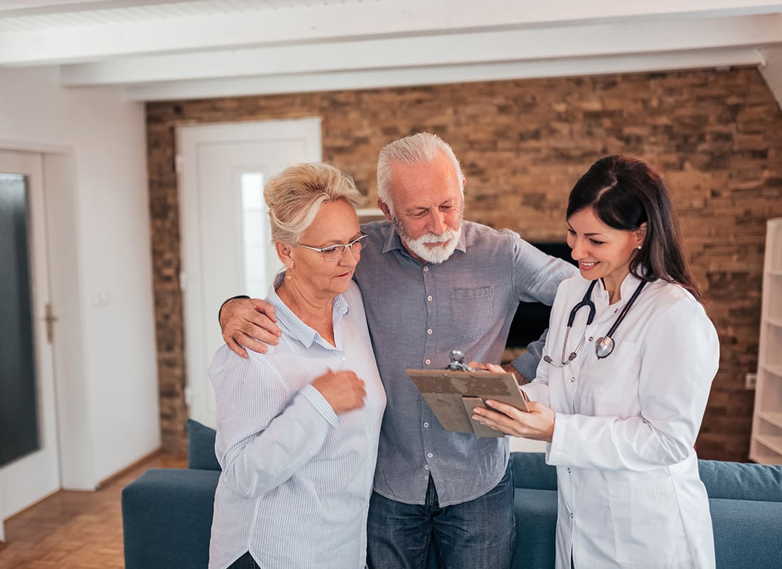 Employee Benefits - Senior Couple Discussing With Female Doctor With While Standing in the Living Room