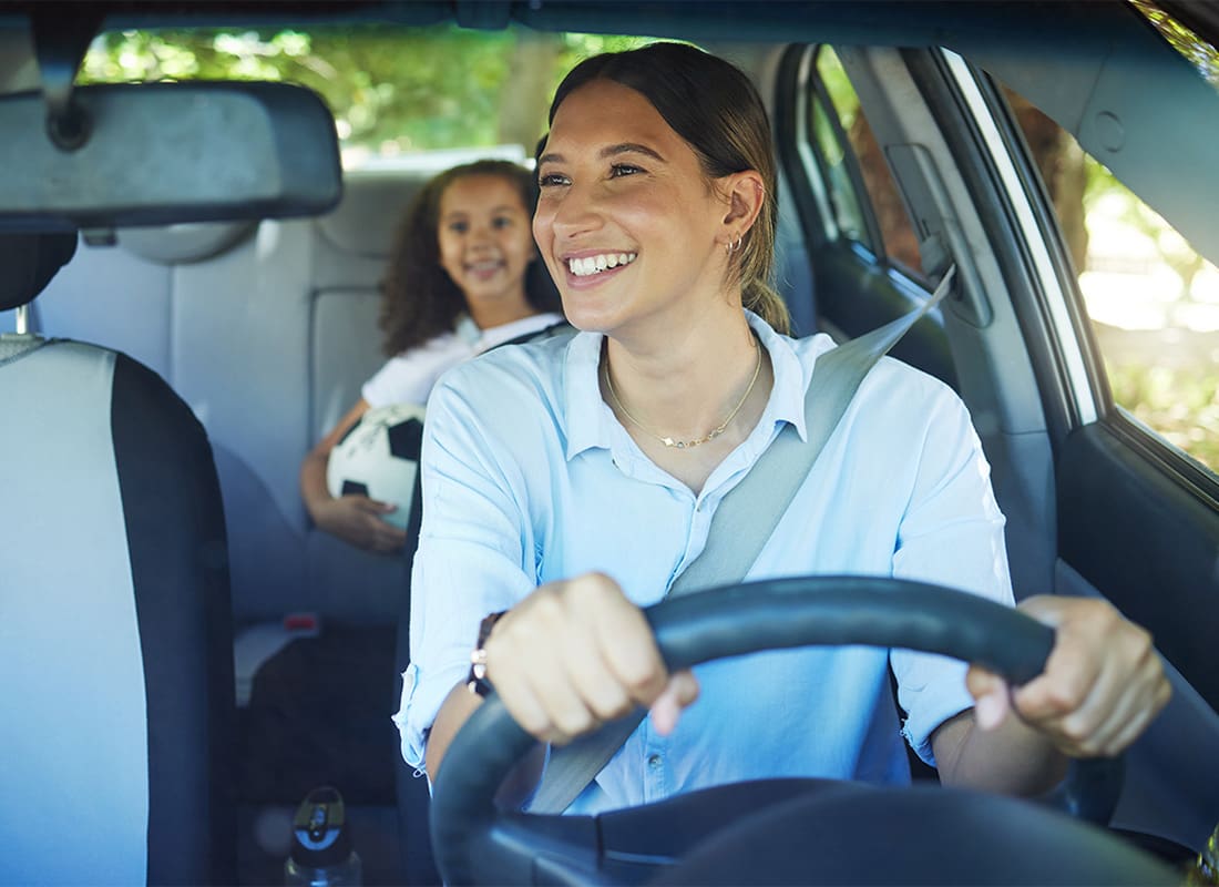 Personal Insurance - Closeup Portrait of a Cheerful Young Mother Driving her Daughter to Soccer Practice